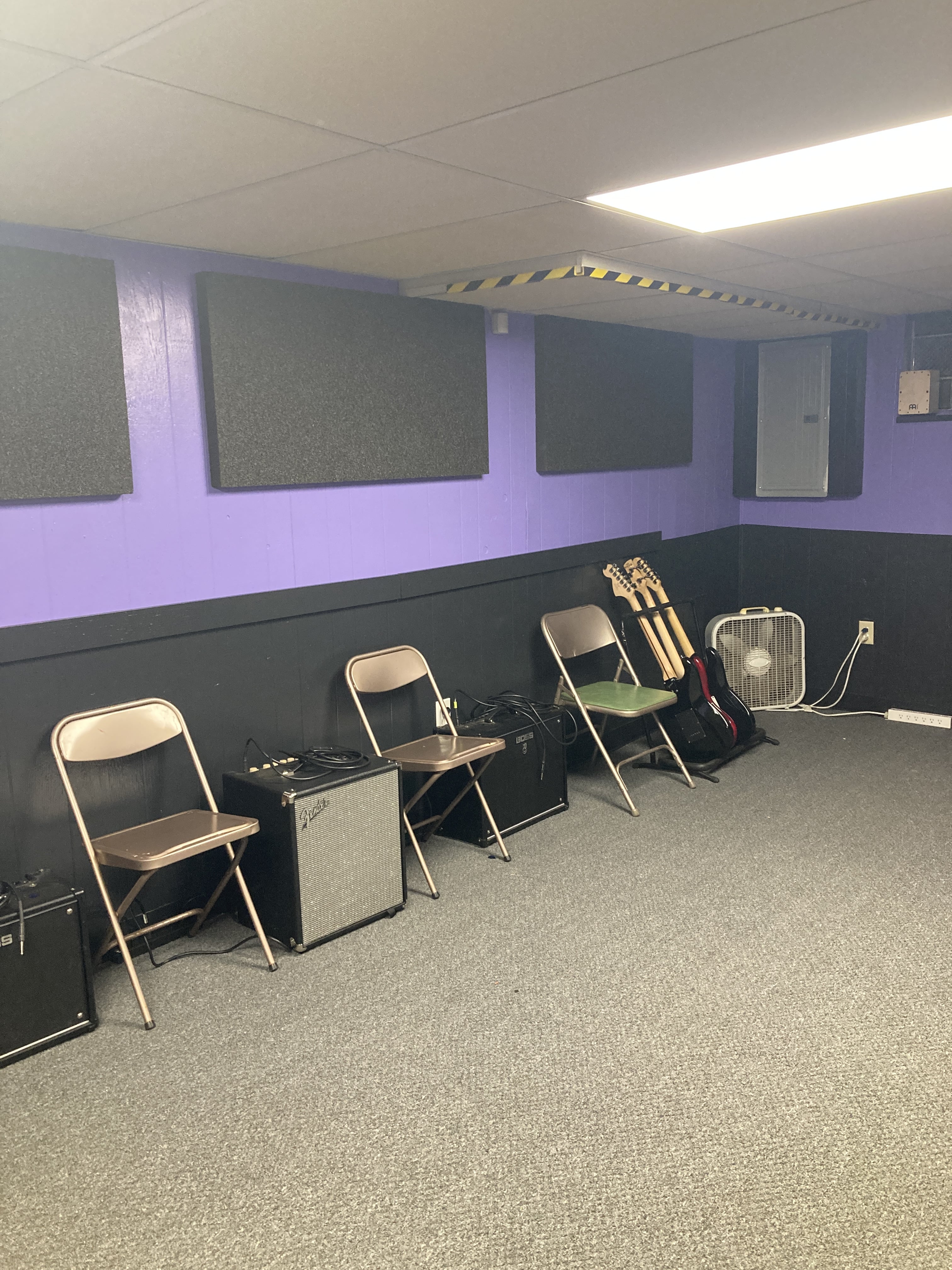 Bass Line Music Studio main room: purple/black walls, black sound panels, light carpet: chairs and amps set up for use