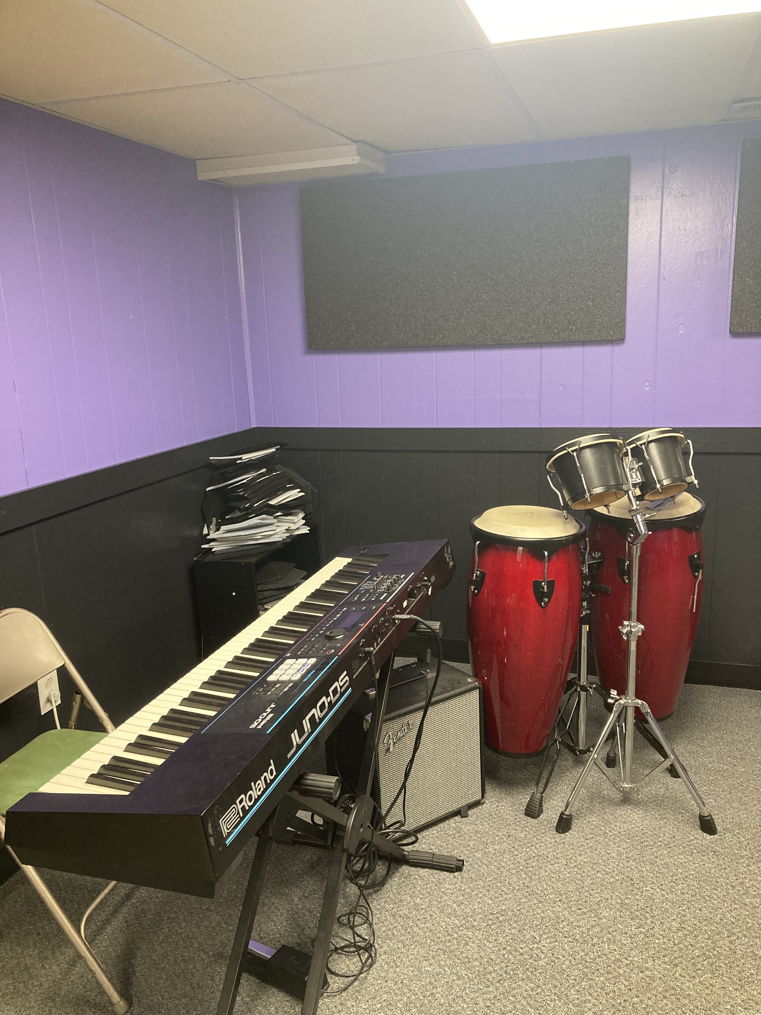 Bass Line Music Studio main room: purple/black walls, black sound panels, light carpet: bongos/congas and keyboard set up for use